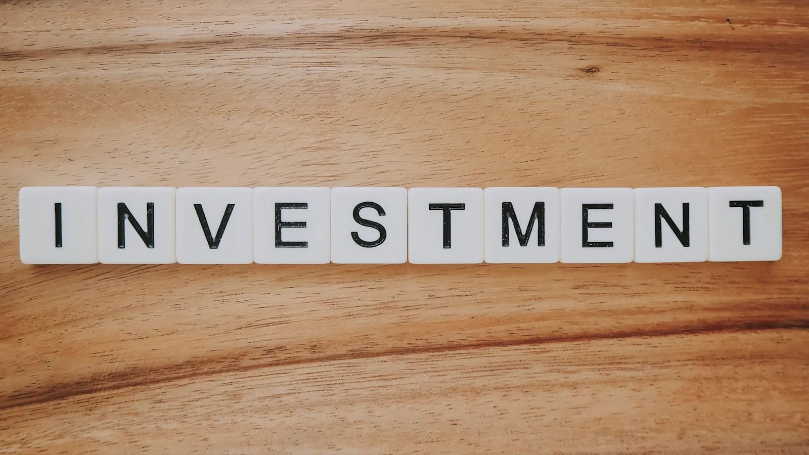 Houten ondergrond met scrabble-tegels die het woord INVESTMENT vormen